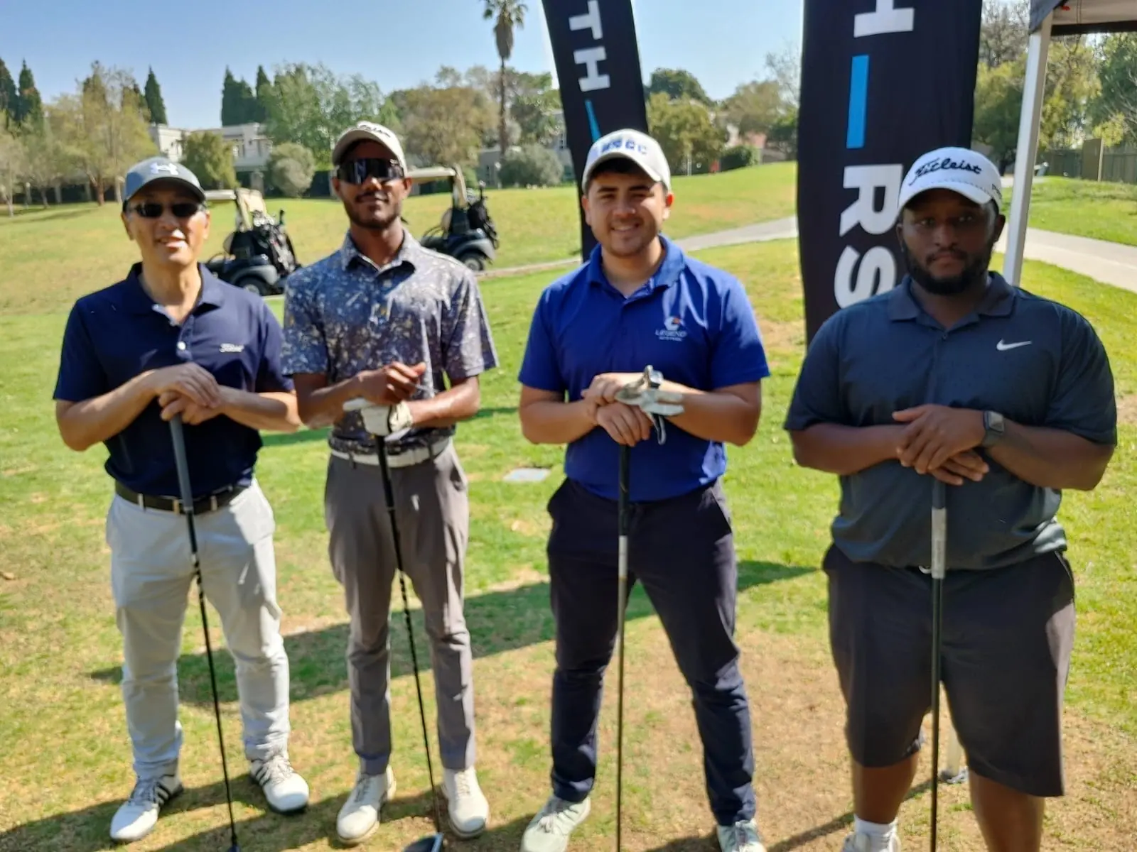 Four golfers in team shirts on the course at The Angel Network Golf Day