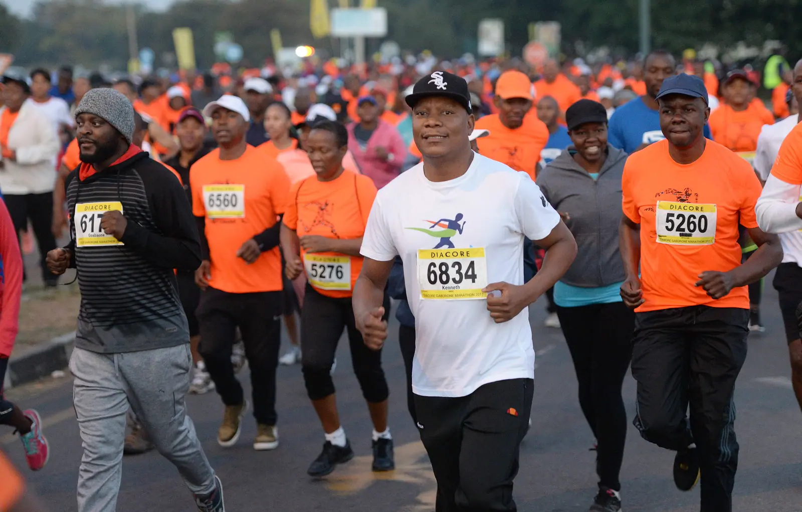 Runners in orange race shirts fill the road at the start