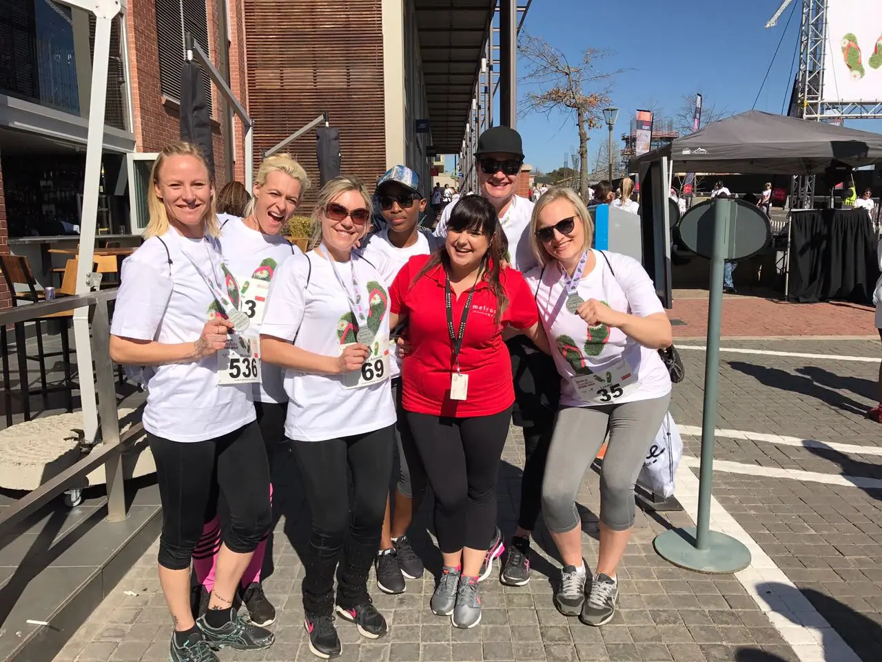 Walkers with race numbers pose on a Melrose Arch street