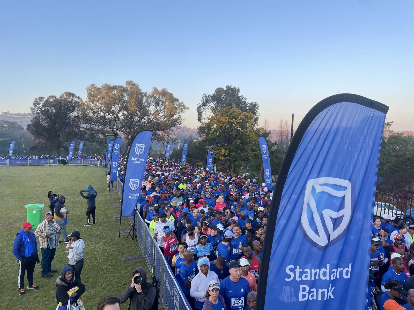 Runners pack the start pen behind Standard Bank flags